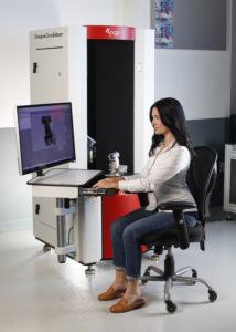 Woman on a office chair using a ShapeGrabber automated scanner which is well suited for situations in which speed and ease of use are important. These Laser Measurement Systems scan parts in a wide variety of materials, colors, and finishes and excel in rapid prototyping, manufacturing, quality control, and reverse engineering applications.